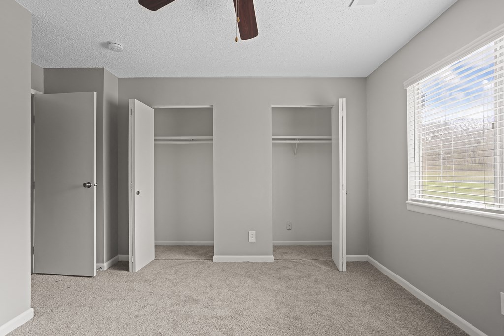 an empty bedroom with three closets and a window