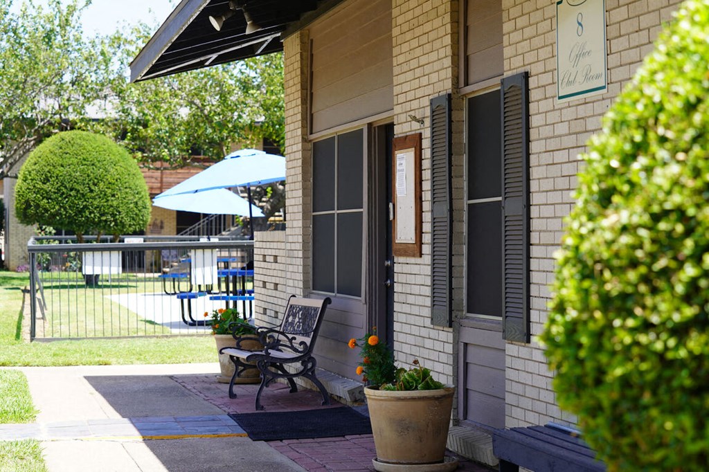 the front porch of a house with a bench and a patio umbrella