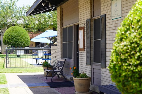 the front porch of a house with a bench and a patio umbrella
