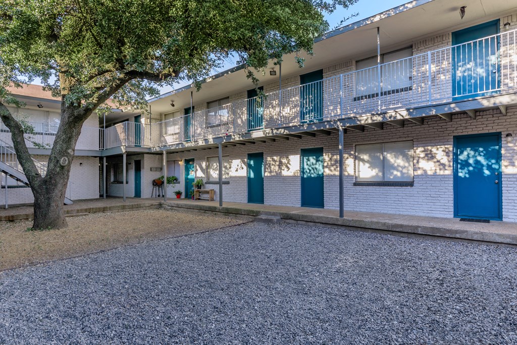 a building with a courtyard and a tree in front of it