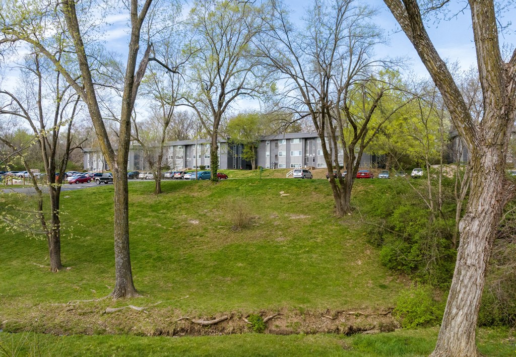 a building on a grassy hill with trees in front of it