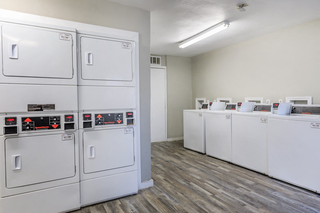 a row of washes and dryers in a room with wood flooring