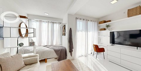A modern bedroom with a large bed, a chair, and a television.