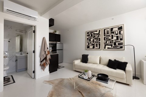 A modern living room with a white couch and a large abstract painting on the wall.