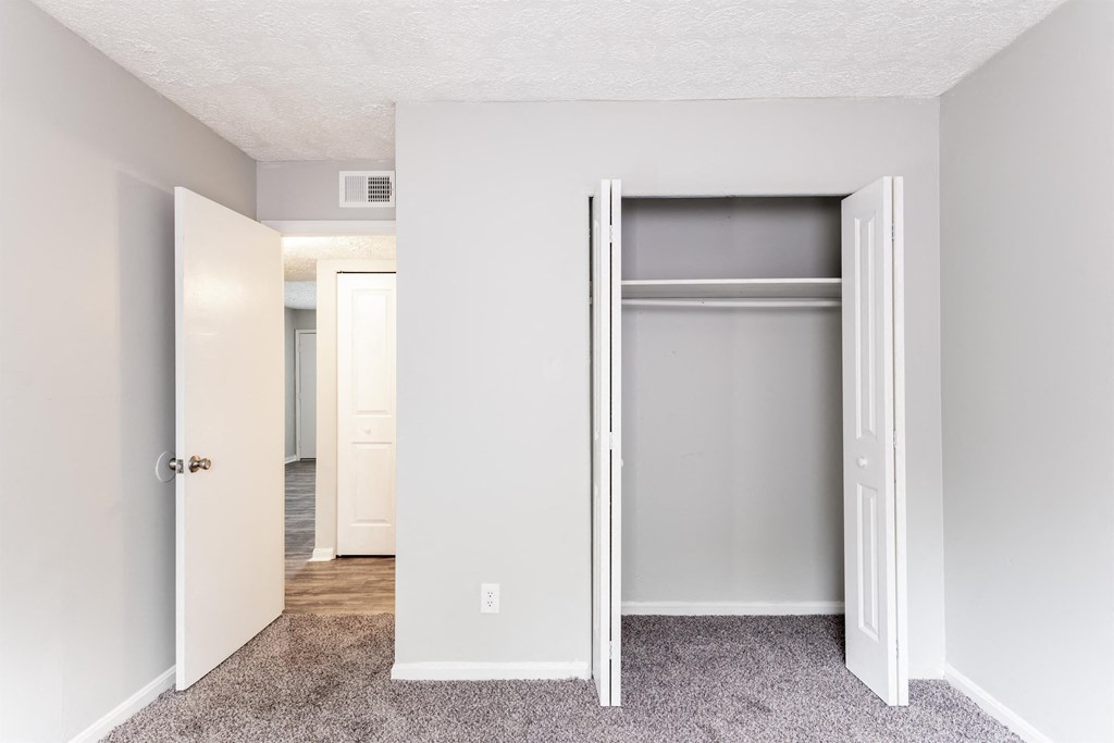 an empty bedroom with an open closet door