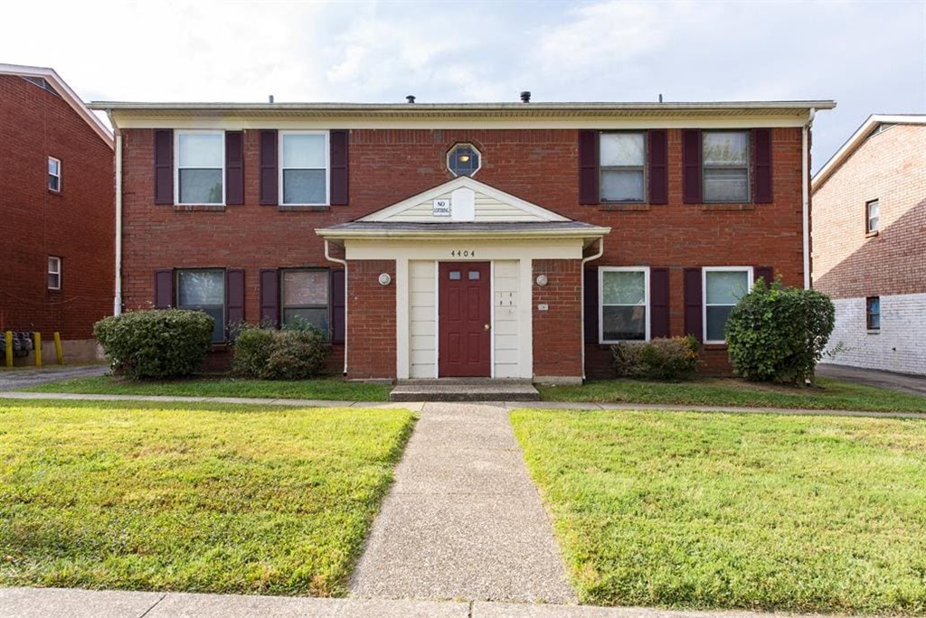 a red brick house with a sidewalk in front of it