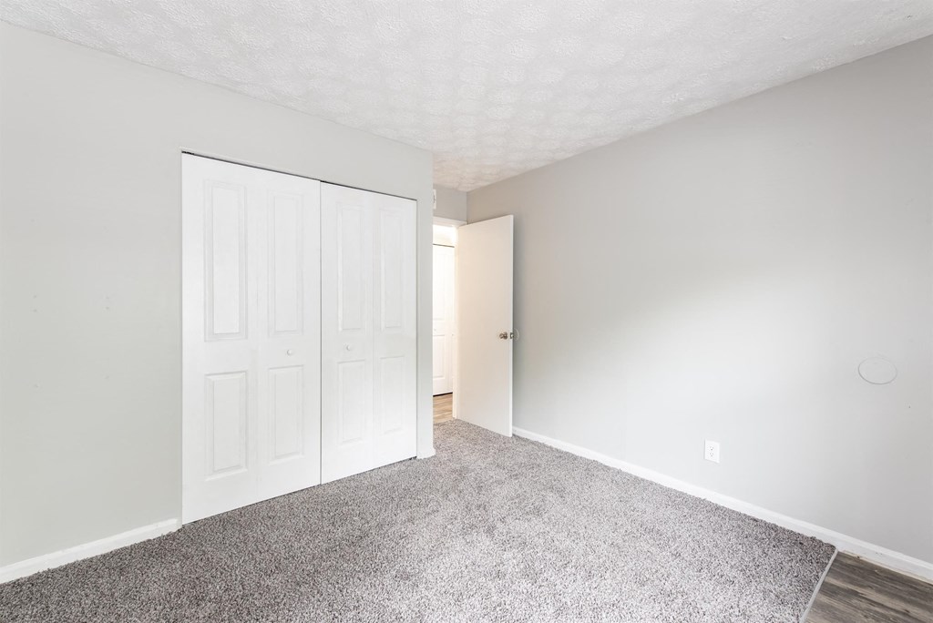 a bedroom with a door to a closet and a carpeted floor