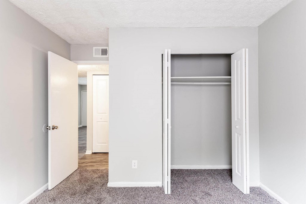 an empty bedroom with an open closet door