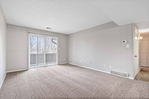A spacious room with a carpeted floor and a sliding glass door.