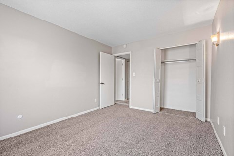 A room with carpeted floor and two doors.