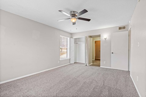 A room with a ceiling fan and carpeted floor.