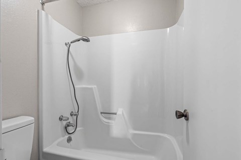 A white bathroom with a tub, toilet, and shower.