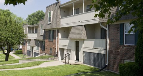 A row of townhouses with a tree in the front yard.