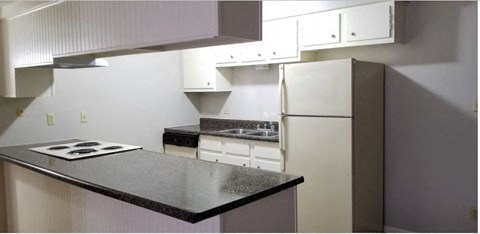A kitchen with a black counter top and white appliances.
