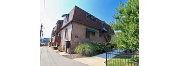A brick building with a green awning and a black fence.