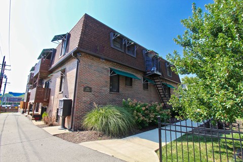 A brick building with a green awning and a black fence in front.