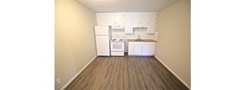 A kitchen area with a white fridge, stove, and cabinets.