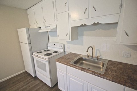A kitchen with white cabinets and a stove top oven.