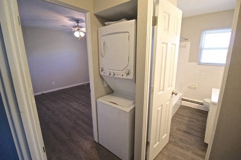A white toilet is in a small room with a door open to a bathroom.