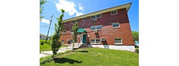 A red brick building with a green awning and a white door.