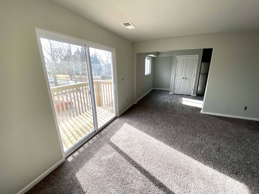 A sunny day with a carpeted room and sliding glass doors.