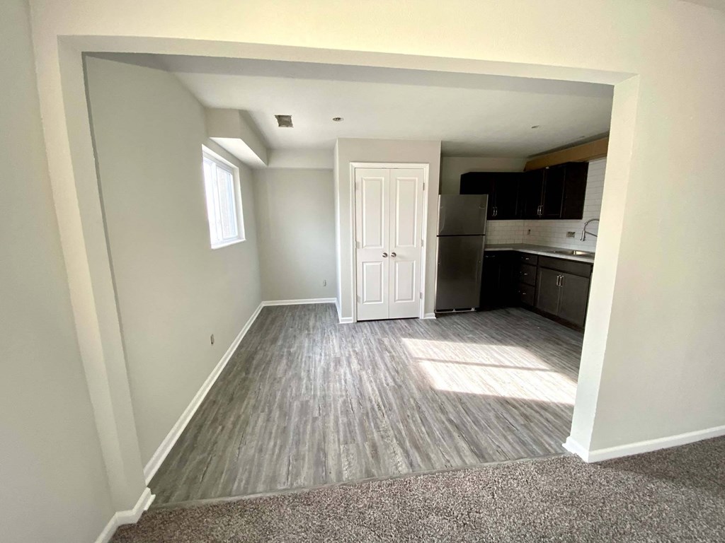 A room with a white door leading to a kitchen.