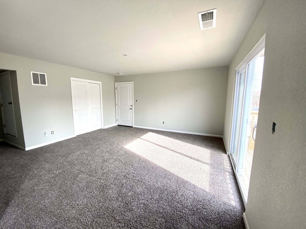 A large empty room with carpeted floor and white walls.