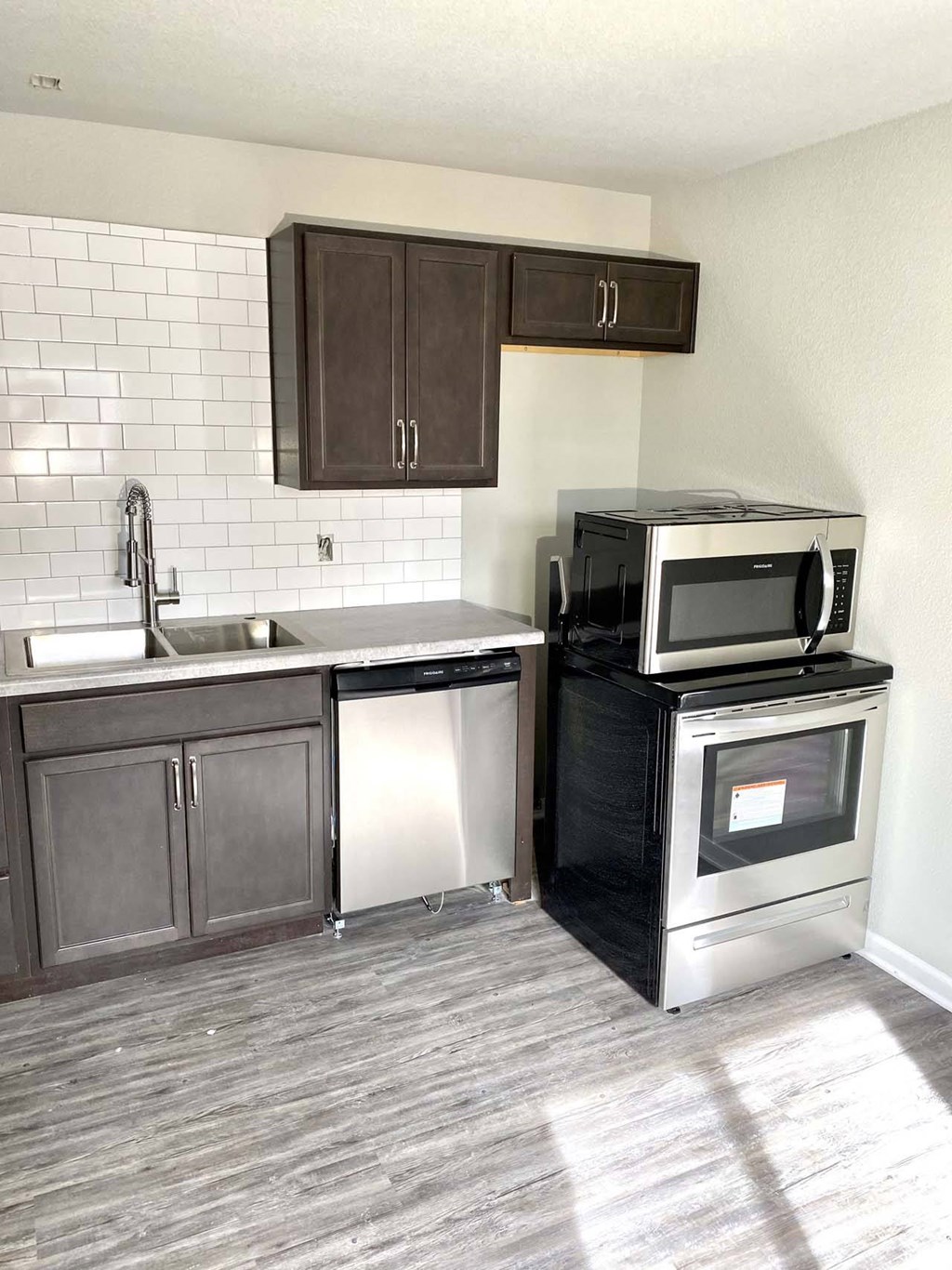A kitchen with a black microwave oven on a black cabinet.