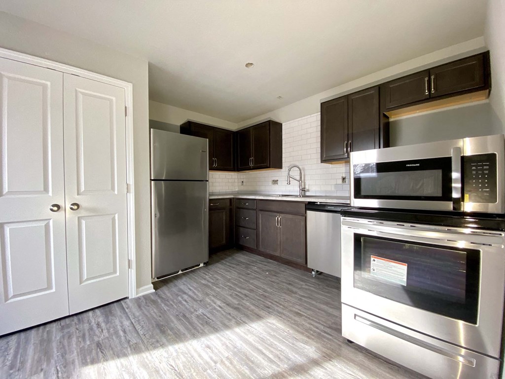 A kitchen with a stainless steel refrigerator, microwave, and oven.