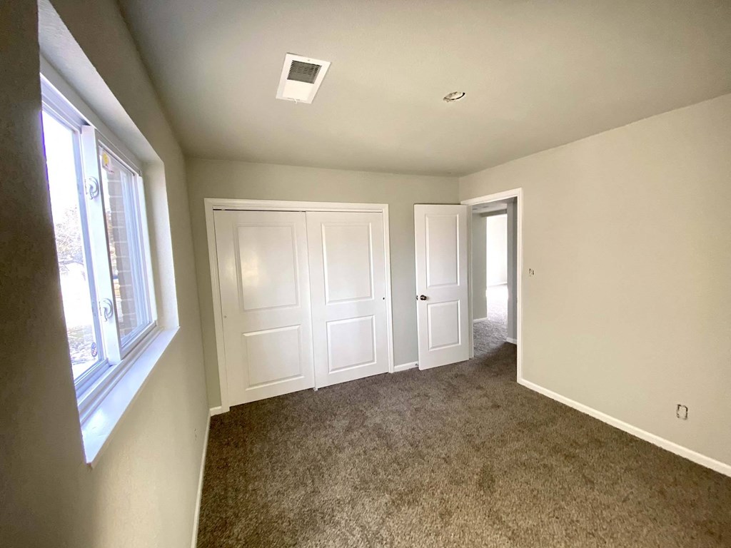A room with carpeted floor and two doors.