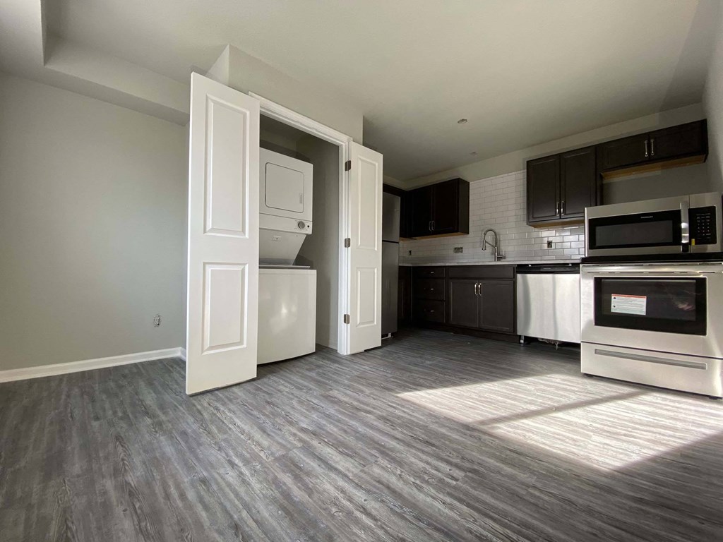A kitchen with a white fridge and microwave, and a wooden floor.