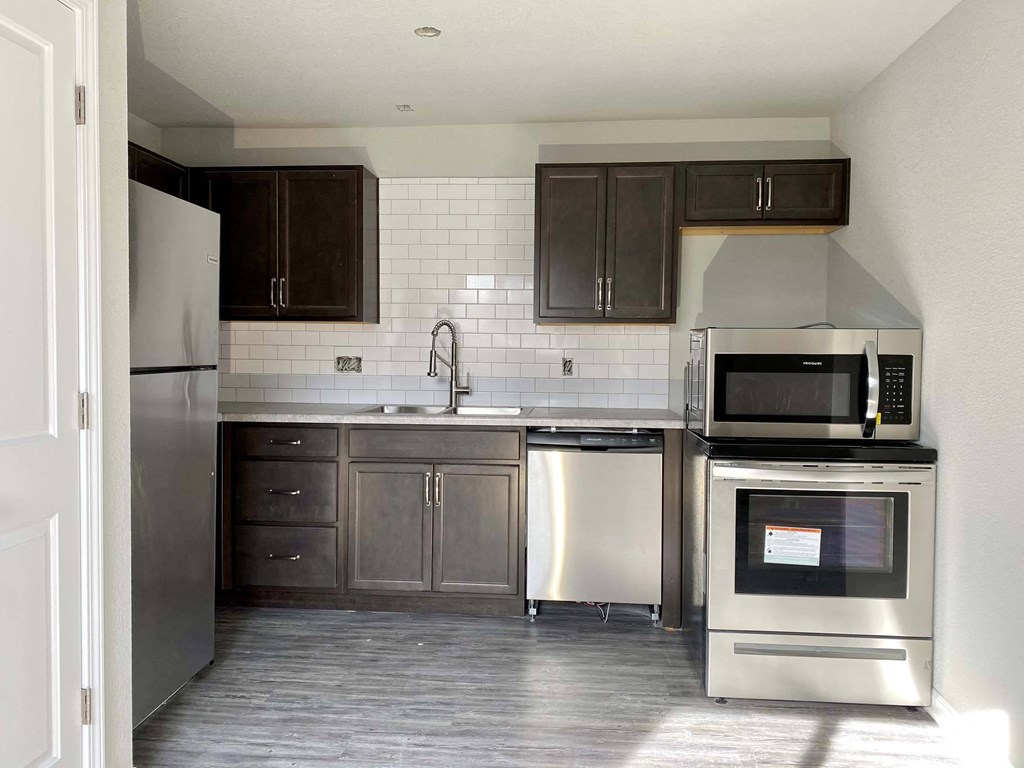 A kitchen with dark brown cabinets and a white tiled backsplash.