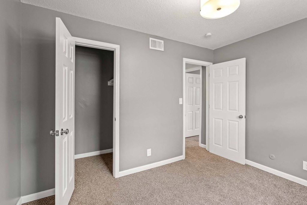 A room with a carpeted floor and two doors, one of which is open.