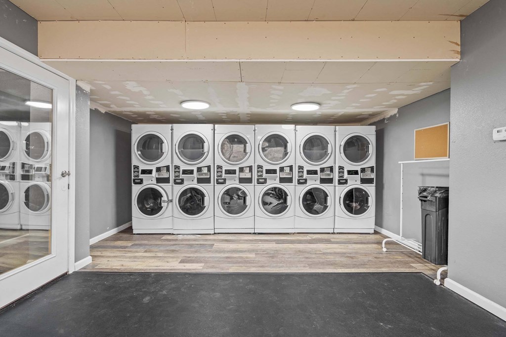 A laundry room with a row of washing machines.