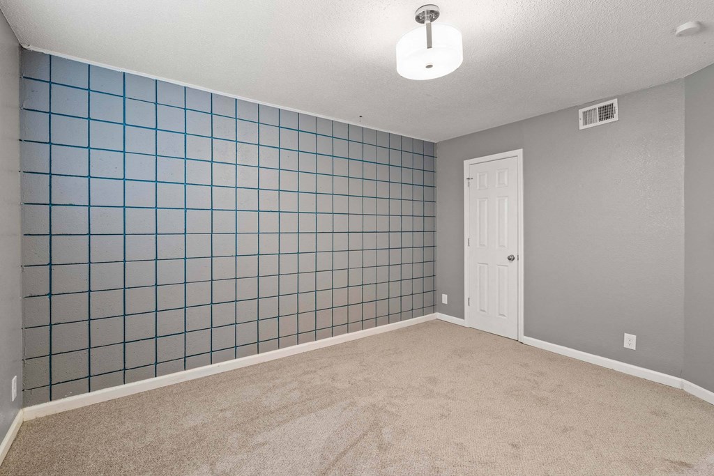 A room with a white door and a blue tile wall.