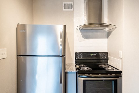 A stainless steel refrigerator and stove top oven in a kitchen.