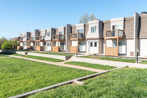A row of modern townhouses with green lawns in front.