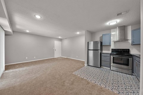 A kitchen with a refrigerator, oven, and stove.