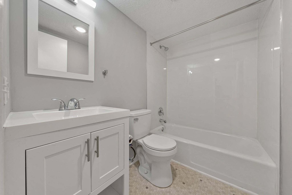 A white bathroom with a toilet, sink, and bathtub.