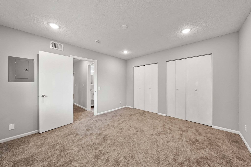 A spacious room with carpeted flooring and white walls.
