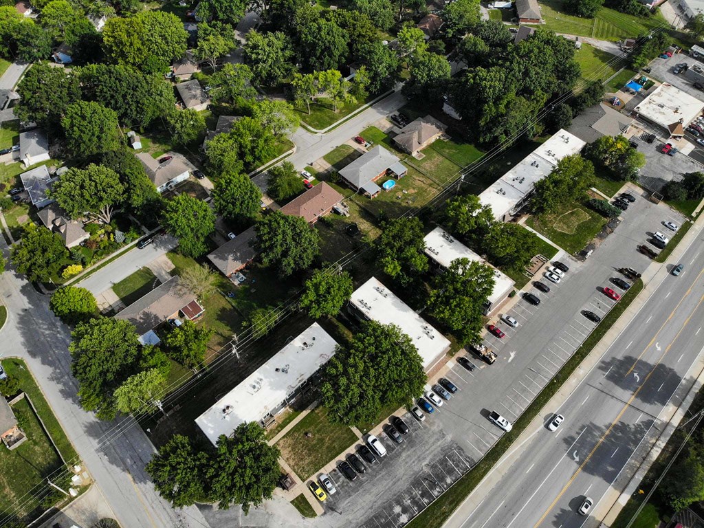A bird's eye view of a residential area with houses, trees, and a parking lot.