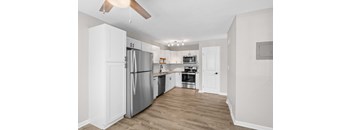 A kitchen with a refrigerator, oven, and sink.