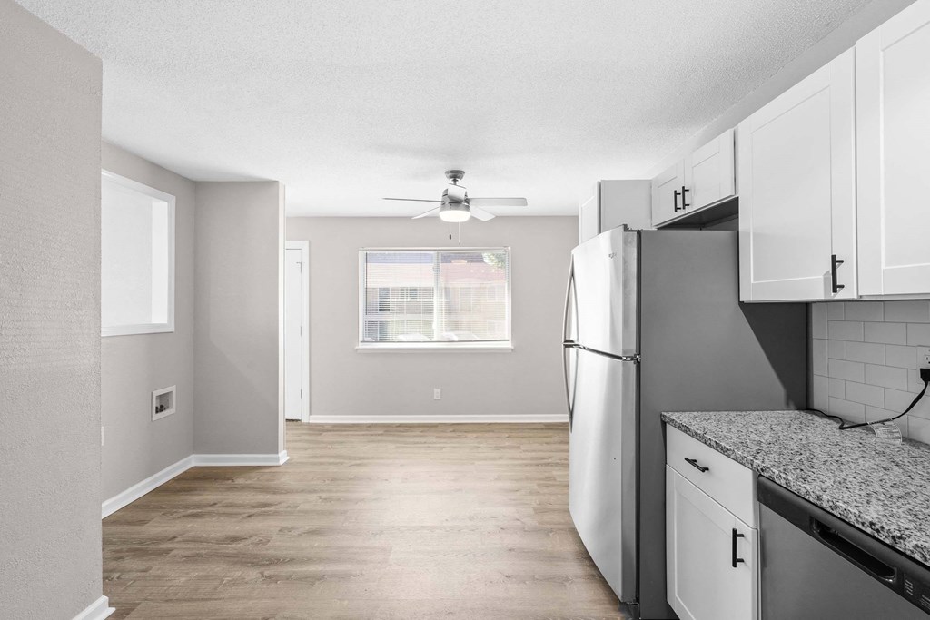 A kitchen with a refrigerator, countertop, and a ceiling fan.