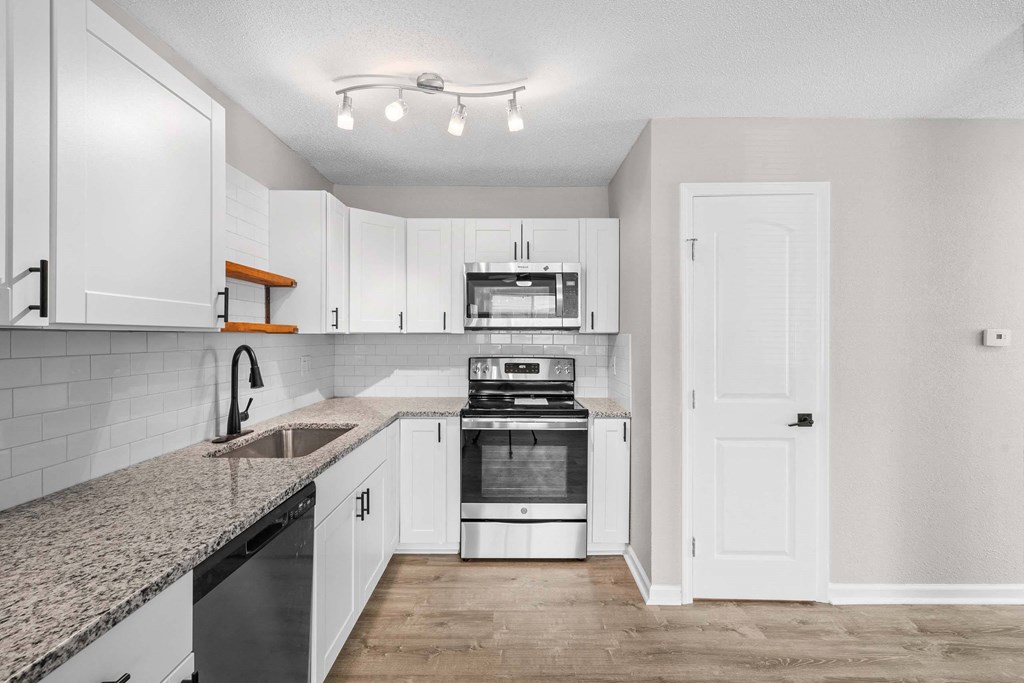 A kitchen with white cabinets and a granite countertop.