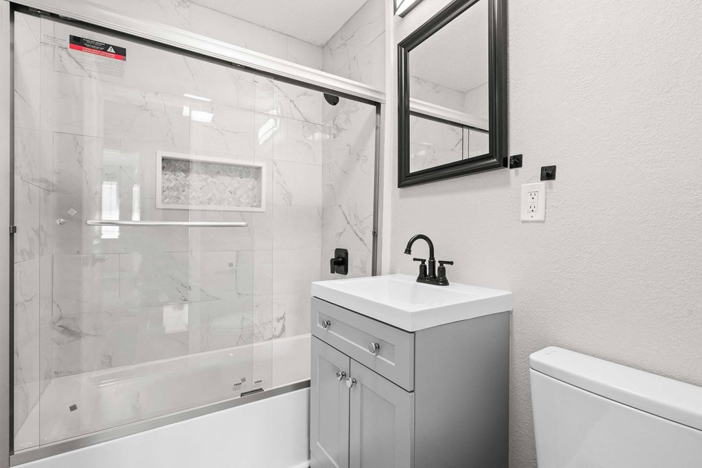 A white sink with a black faucet is on a white countertop in a bathroom.