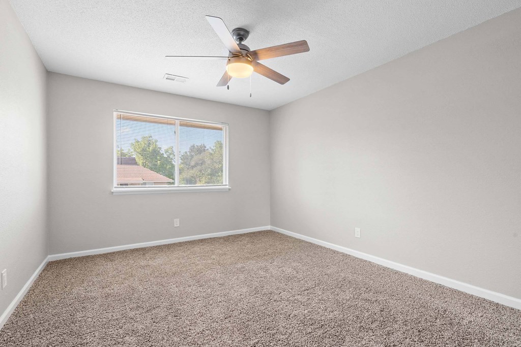 A room with a ceiling fan and carpeted floor.