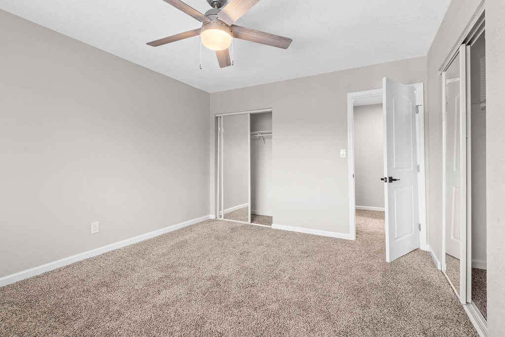 A room with a ceiling fan and carpeted floor.