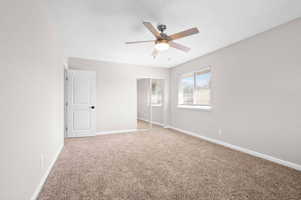 A room with a ceiling fan and carpeted floor.