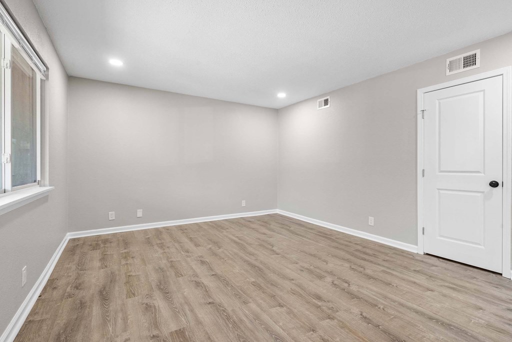 A room with a white door and wooden flooring.
