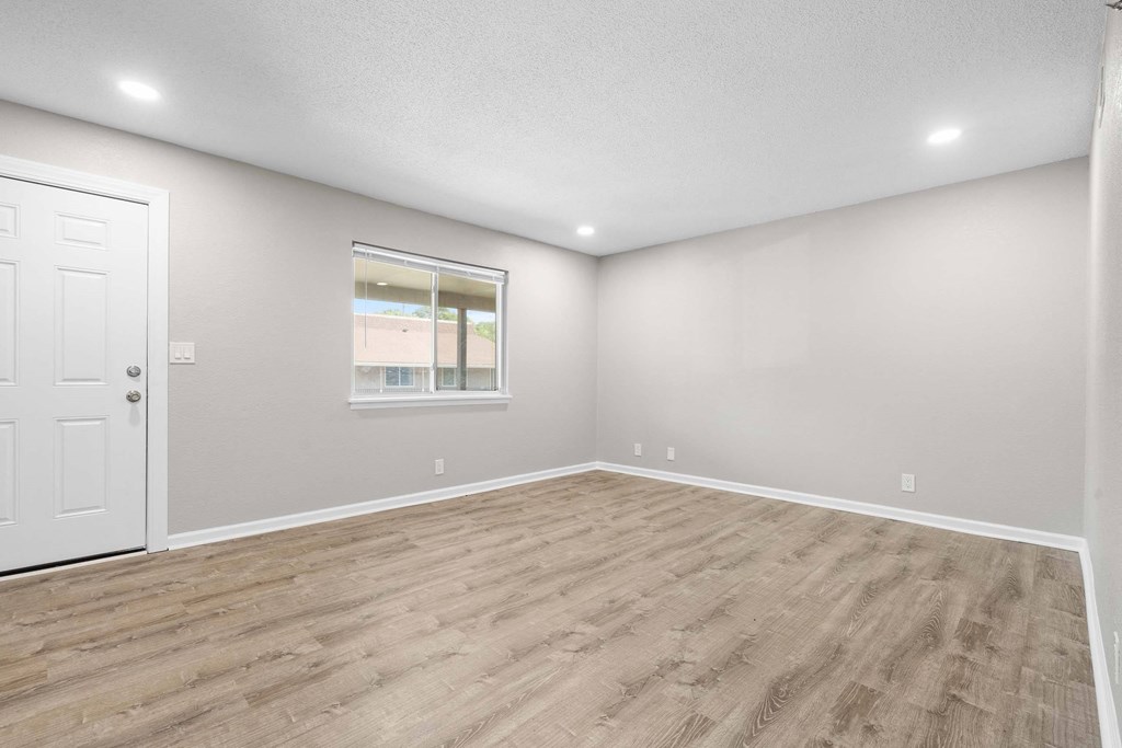 A room with a white door and a window with a view of a building.